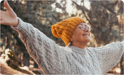 Elderly person with arms wide open enjoying the winter